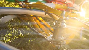 Closeup of spinning Google bike wheel on top of grass. There is a soft stream of light coming from the right side of the image.