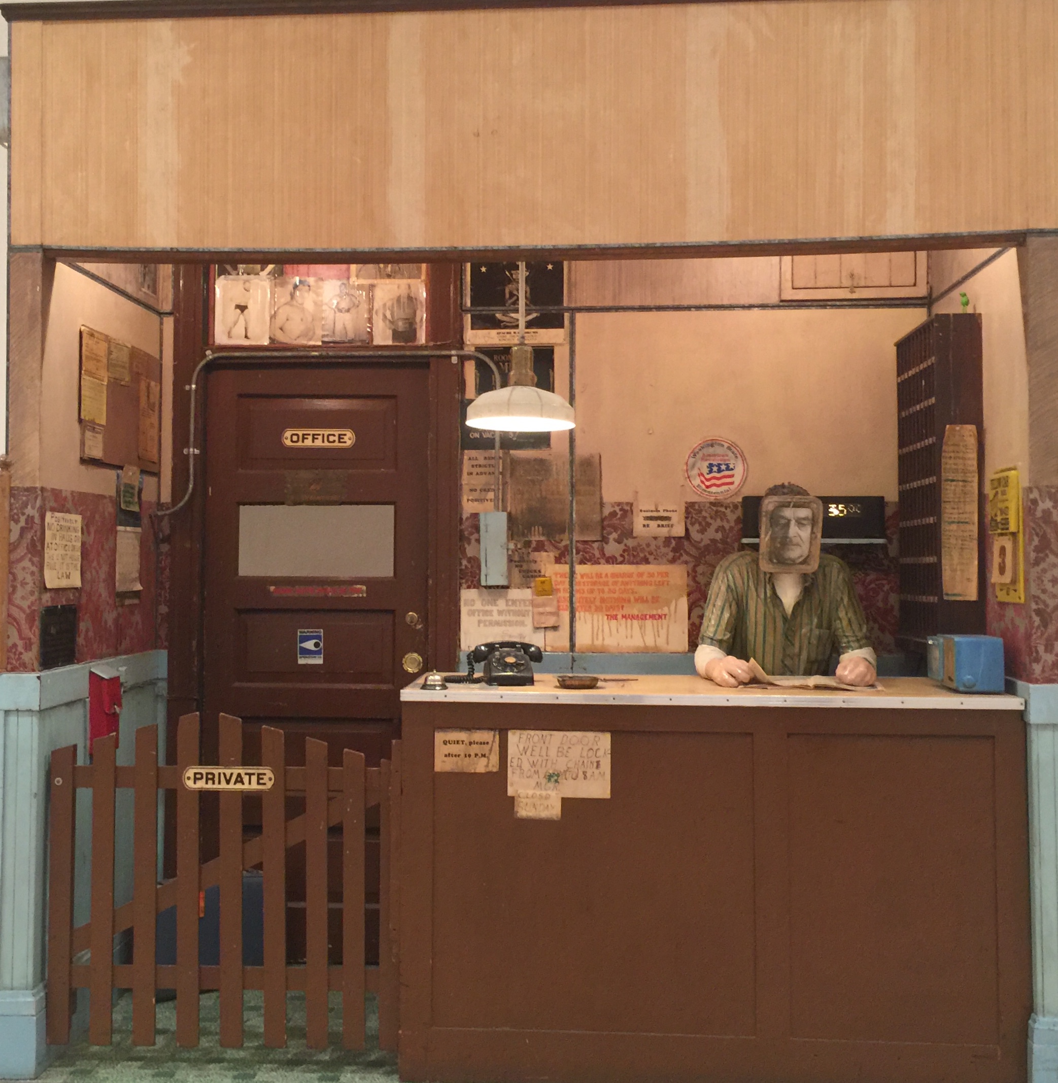 Art piece display a night clerk in a setting resembling a decrepit hotel office