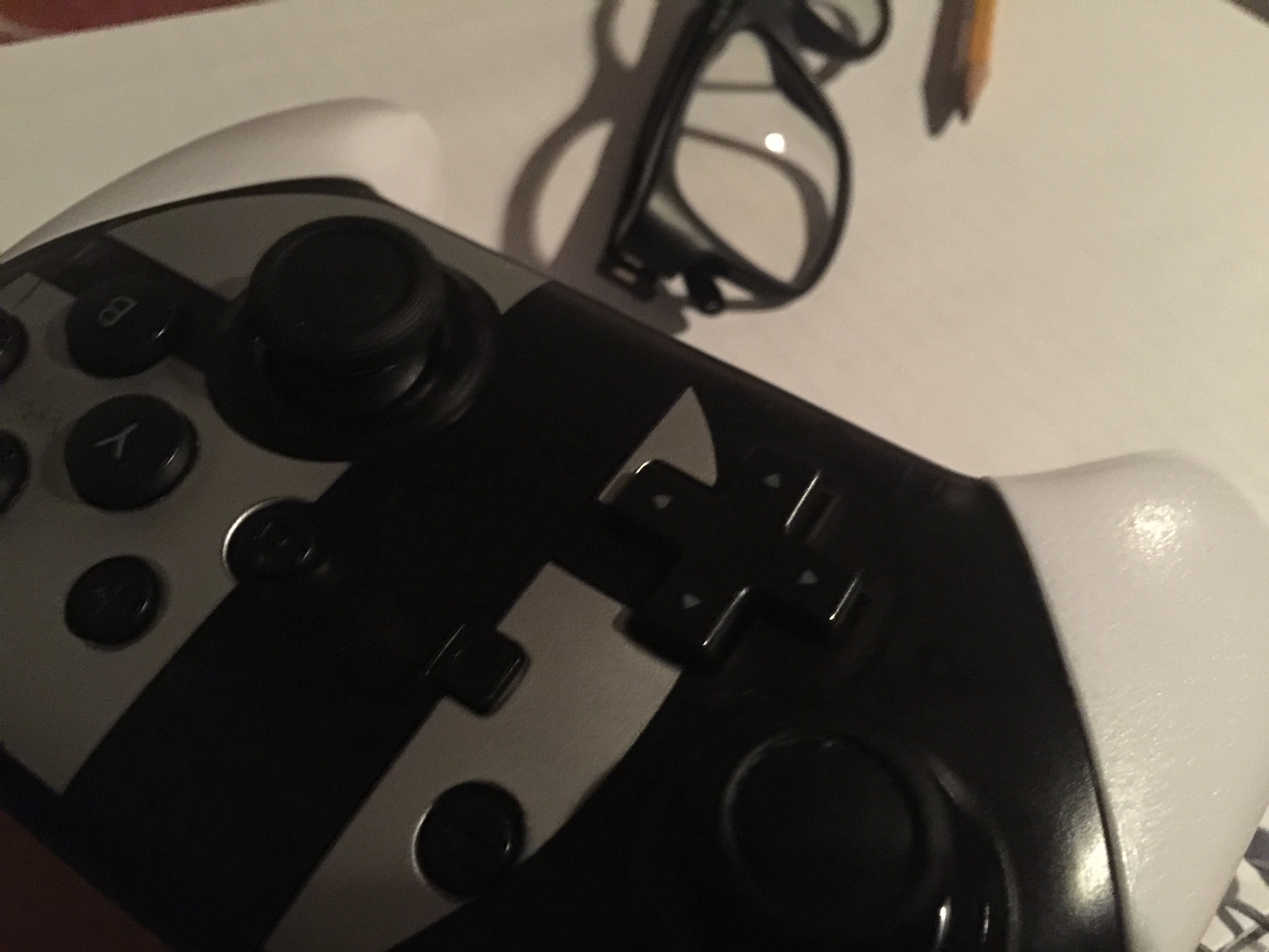 An image with a game controller, glasses, and a pencil on top of a notebook.