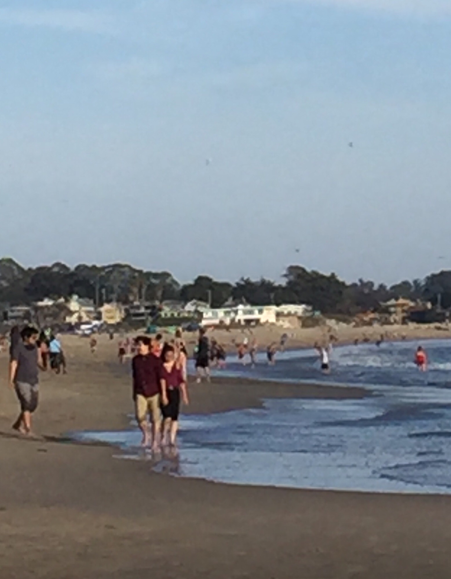 An image of the beach with several people walking barefoot in the distance.