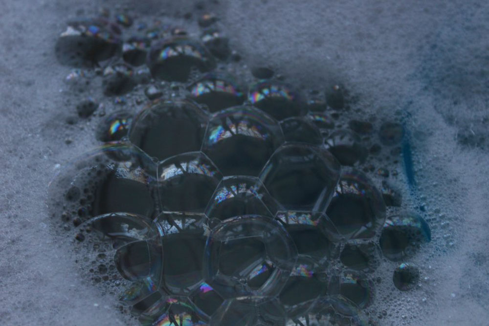 The photo shows bubbles in a sink with the reflection of the window in them.