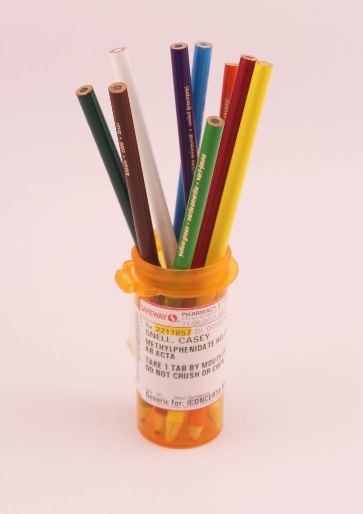 A pill bottle filled with colored pencils