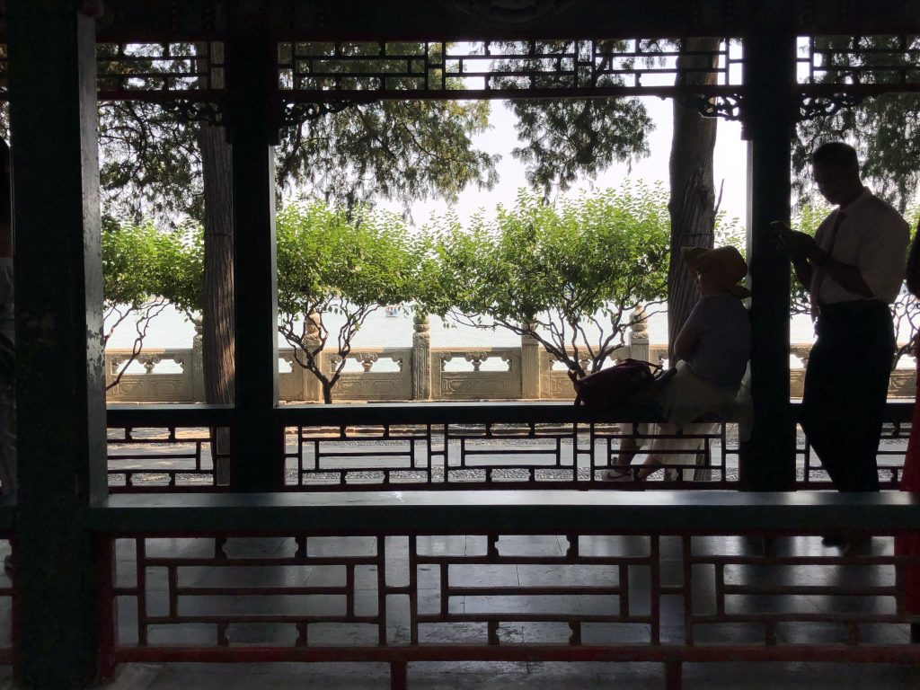 This photo shows an archway with people sitting on the benches, looking out into the distance. 