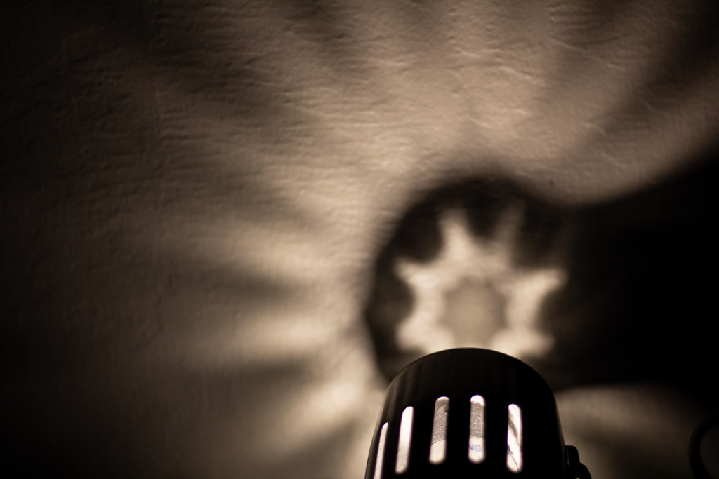 Lamp casting a star-like shadow onto the wall in the dark.