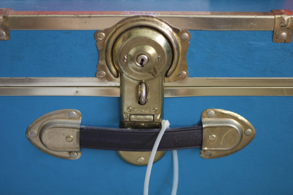 Blue chest with a large lock on it made from brass or a similar metal.