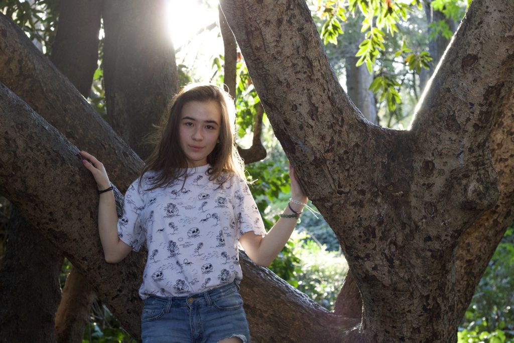 Girl in between trees, light coming from behind girl is on the upper left rule of thirds point