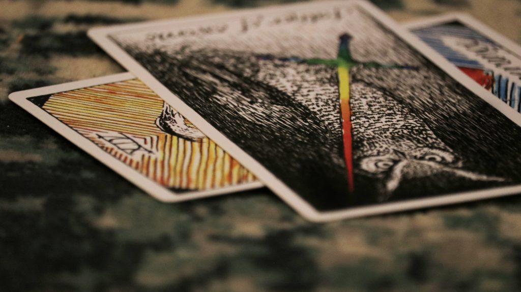 Tarot cards with an owl and rainbow colored sword. 