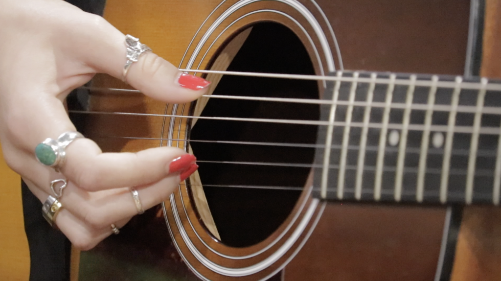 a close up of a girl's hands playing guitar