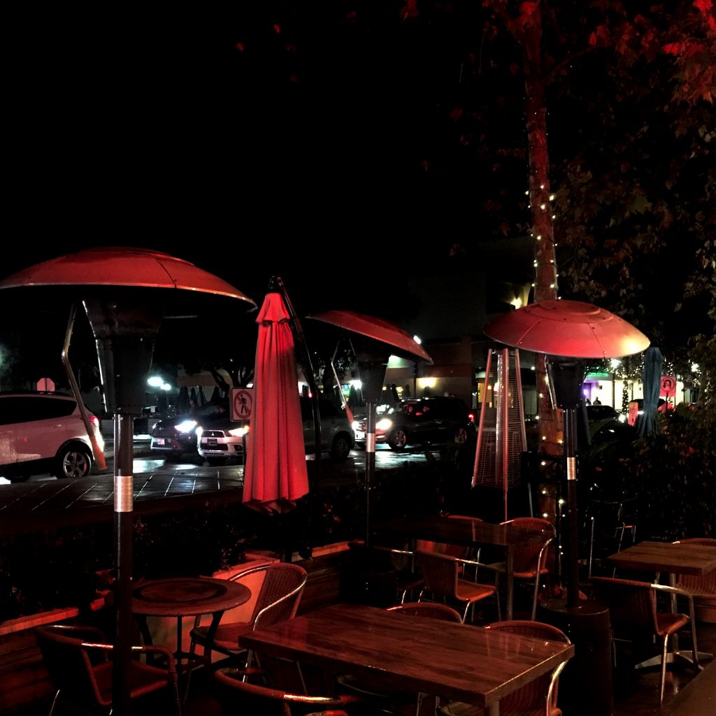 Streetside dining lit in red lights.