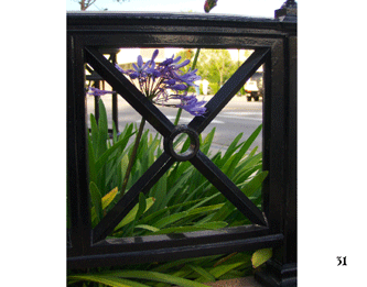 A flower sticking through a metal fence