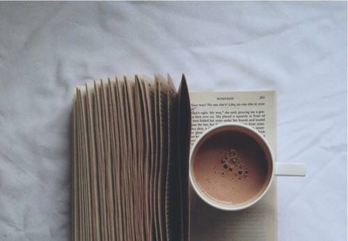 An open book with a cup of coffee on it.