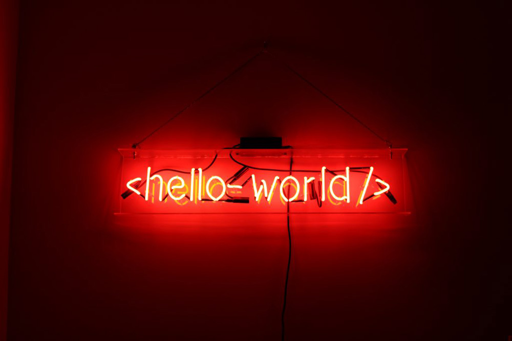 A photo of a lit up red neon sign that says "hello-world". The image represents a sense of warmth and comfort that was brought to my friends and I as we chilled on a lady Sunday evening.