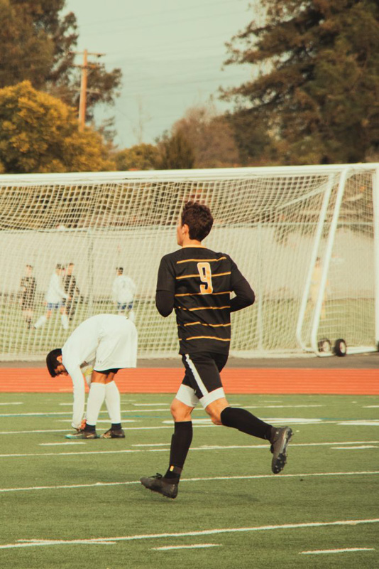 A photo of a soccer player running on a field.