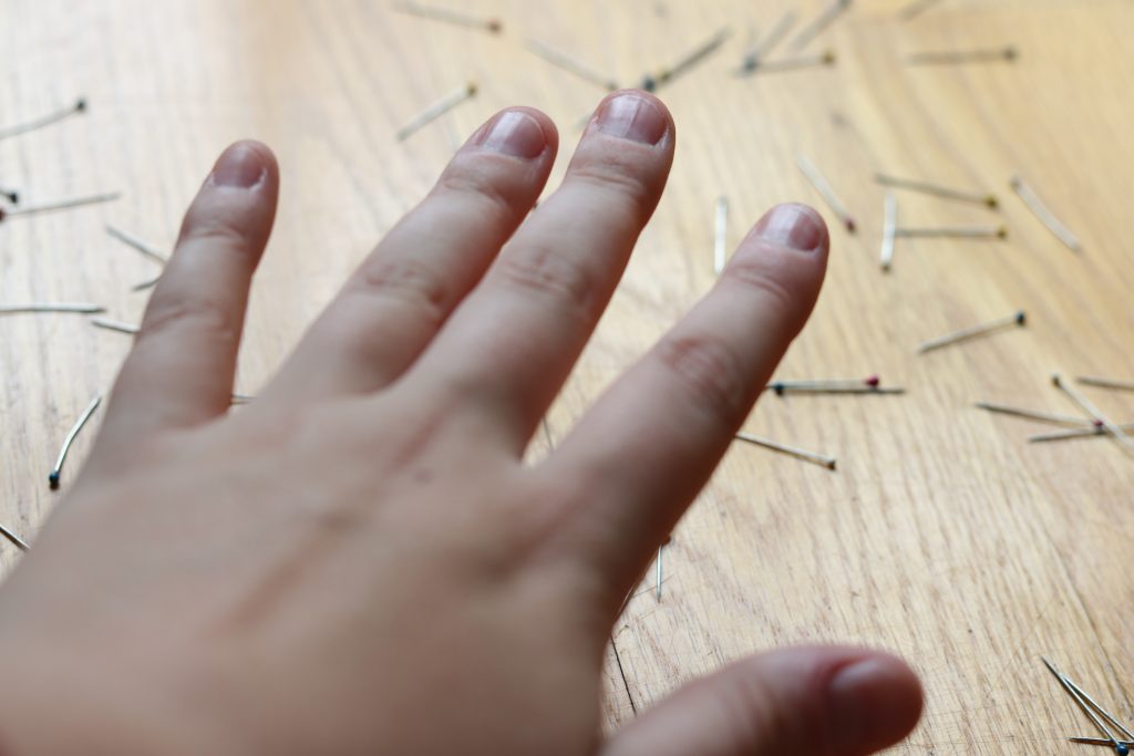 A hand above a bunch of needles