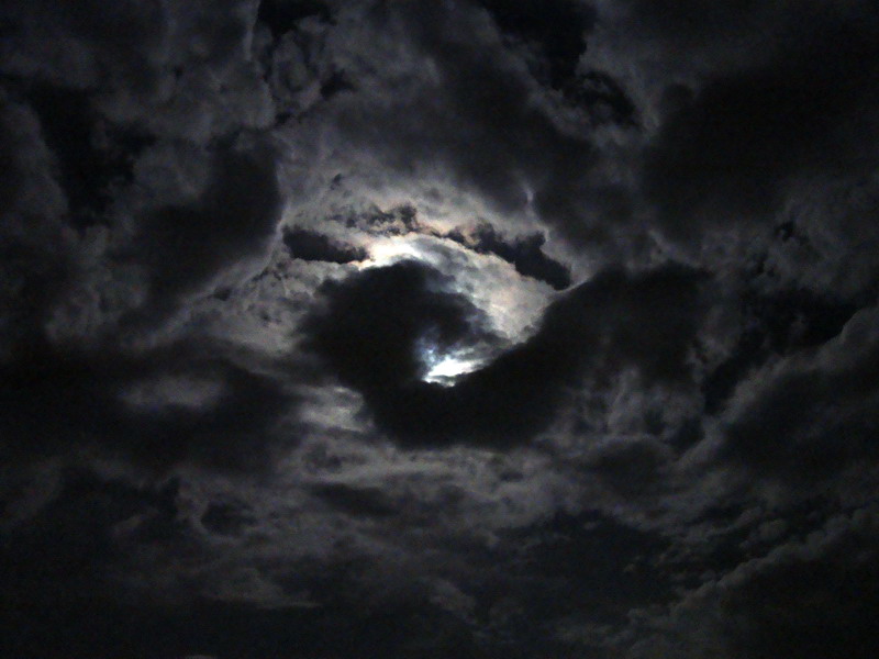The image shows clouds covering the moon in a swirl formation. 